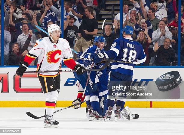 Rene Bourque of the Calgary Flames skates back to the bench as Ryan Malone of the Tampa Bay Lightning celebrates his goal with teammates Steven...
