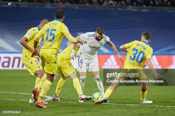 Alvaro Bastida of Cadiz CF and his teammate Alex Fernandez tackle Karim Benzema of Real Madrid CF during the LaLiga Santander match between Real...