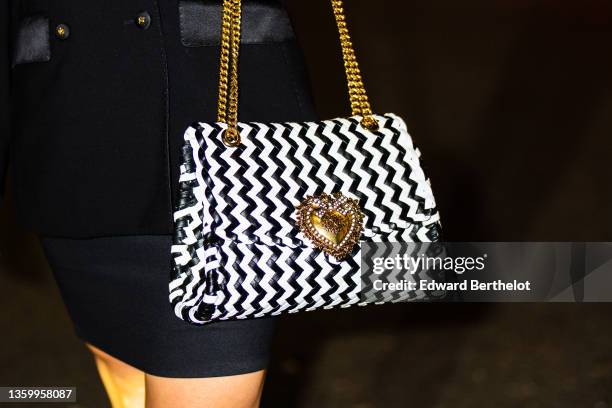 Passerby wears a black long blazer jacket from Dolce and Gabbana, a black short tube skirt, a black and white braided leather handbag from Dolce and...