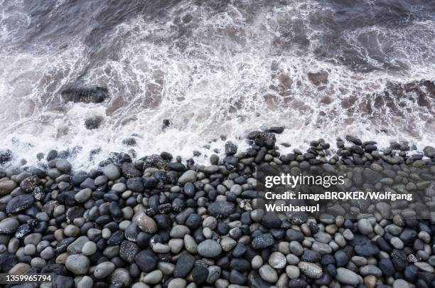drone shot, surf with big round stones on the beach of rocha da relva, sao miguel island, azores, portugal - relva stock-fotos und bilder