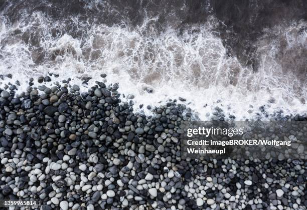 drone shot, surf with big round stones on the beach of rocha da relva, sao miguel island, azores, portugal - relva stock-fotos und bilder