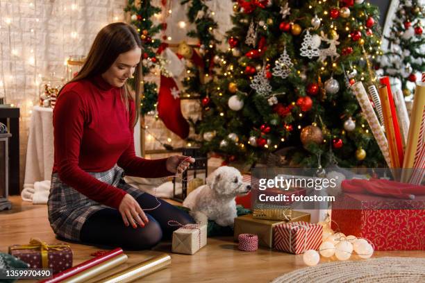 kopieren sie eine weltraumaufnahme der jungen frau, begleitet von ihrem süßen hund, die weihnachtsgeschenke einwickelt und dekoriert - dog knotted in woman stock-fotos und bilder