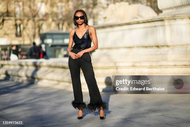 Emilie Joseph @in_fashionwetrust wears black sunglasses, a black sequined / shiny glitter V-neck tank-top, silver earrings, high waist black large...