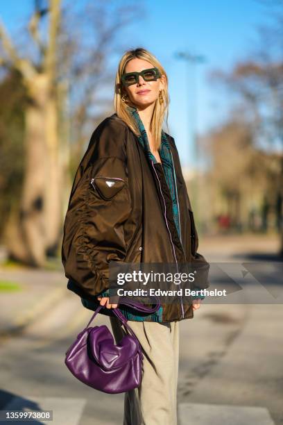 Natalia Verza wears khaki sunglasses, gold earrings from Fendi, a black star patterns cut out and linked together V-neck tank-top, high waits beige...