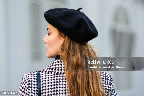 Olesya Senchenko wears black felt / wool beret, a black wool turtleneck pullover, a black and white houndstooth print pattern blazer jacket, a black...