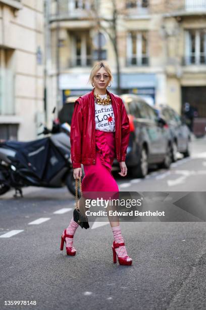 Emy Venturini wears large gold earrings, gold sunglasses from Prada, a large gold flowers necklace, a white with black inscriptions and red...
