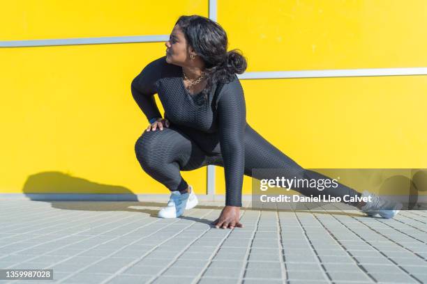 fit woman stretching in the street - curvy black women stockfoto's en -beelden