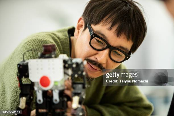 an engineer at a start-up company checks out a prototype robot - プロトタイプ ストックフォトと画像