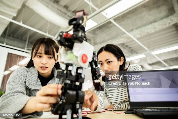 a female researcher at a start-up company examining a robot prototype - aprendizaje automático fotografías e imágenes de stock