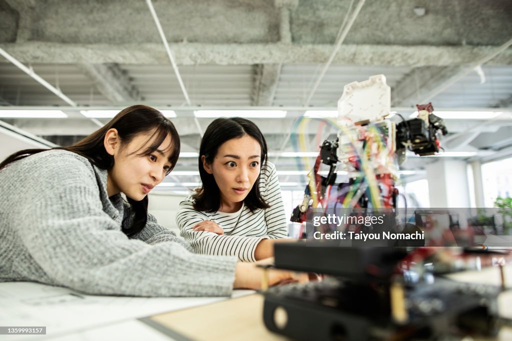 A female researcher at a start-up company examining a robot prototype