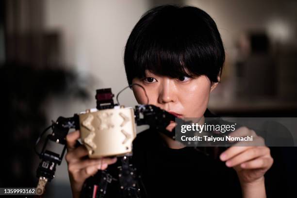 a female researcher adjusts a robot prototype in the lab - アンドロイド ストックフォトと画像