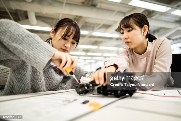 female employees of a start-up company disassemble a robot prototype - disassembling stock pictures, royalty-free photos & images