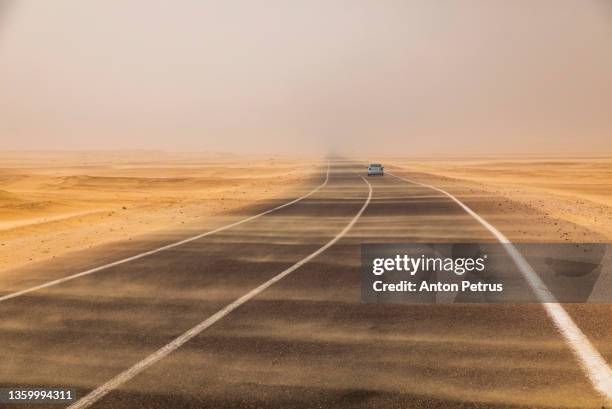 sand storm over the road in the desert. strong wind and dust clouds on the road - road to war in middle east and north africa stock-fotos und bilder