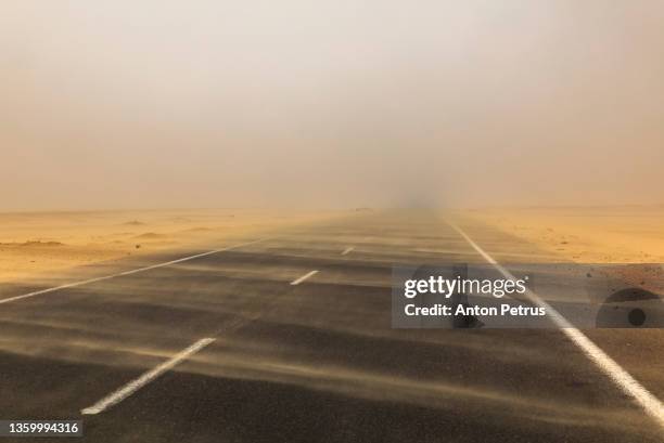 sand storm over the road in the desert. strong wind and dust clouds on the road - dust storm stock pictures, royalty-free photos & images