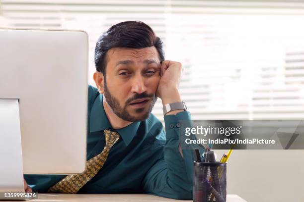 a corporate employee in formal clothing sitting behind desktop screen with drowsy eyes about to sleep. - formal shirt stock pictures, royalty-free photos & images