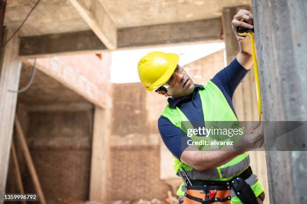 workman wearing yellow vest and hardhat working at construction site - house inspection stock pictures, royalty-free photos & images