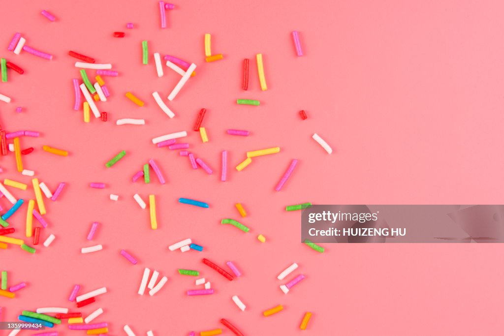 Colorful candy sprinkles on pink background