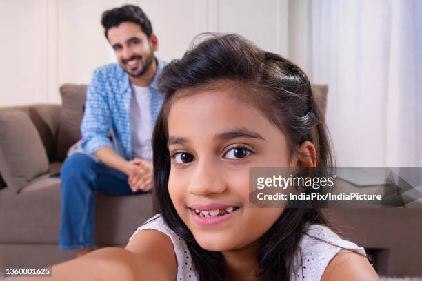 a happy daughter clicking selfie while father sits behind - father clicking selfie stock pictures, royalty-free photos & images