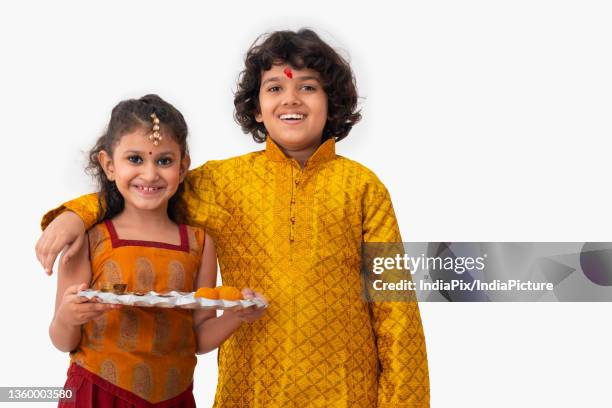 portrait of sibling posing in front of camera while holding a plate on bhai dooj - bhai dooj festival celebration foto e immagini stock