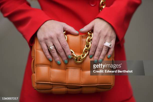 Maria Rosaria Rizzo wears a neon red blazer jacket, matching neon red slit / split suit pants, an orange shiny leather quilted / braided Cassette...