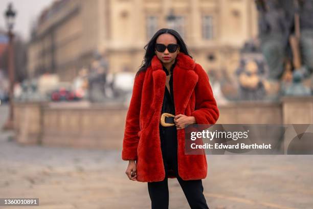 Emilie Joseph @in_fashionwetrust wears black sunglasses, gold large earrings, a black transparent silk V-neck / long puffy sleeves shirt, a red...