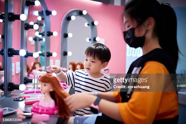 little boy is learning comb hair with sister - chinese dolls stock pictures, royalty-free photos & images