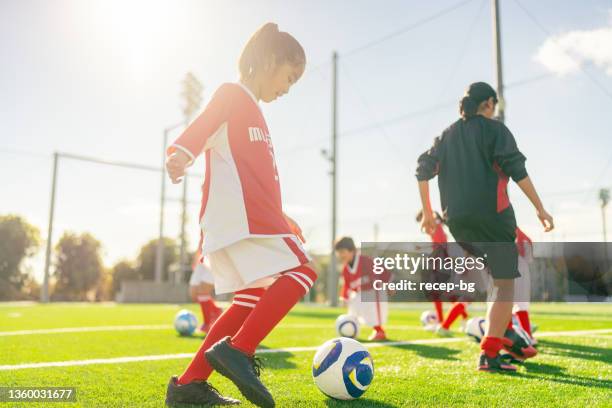 女子子供サッカー・サッカーチームのメンバーは、スキルを向上させるためにトレーニングとドリブルを行います - サッカー 日本人 ストックフォトと画像