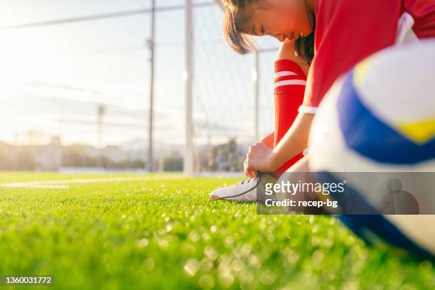 joueuse de soccer ou de football d’âge élémentaire attachant ses chaussures de football ou de soccer avant de commencer l’entraînement - lacet de chaussures photos et images de collection