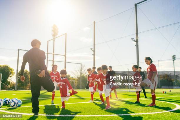members of female kids' soccer or football team warming up before starting training - association of east asian relations and japan stock pictures, royalty-free photos & images