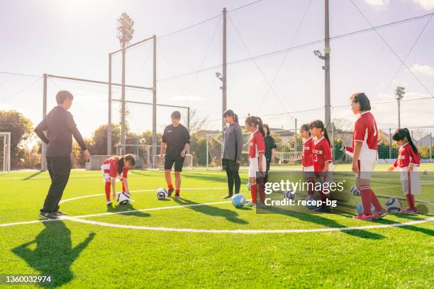 トレーニングを述べる前に、コーチのインストラクターに耳を傾ける女子子供サッカーまたはサッカーチームのメンバー - japan soccer ストックフォトと画像