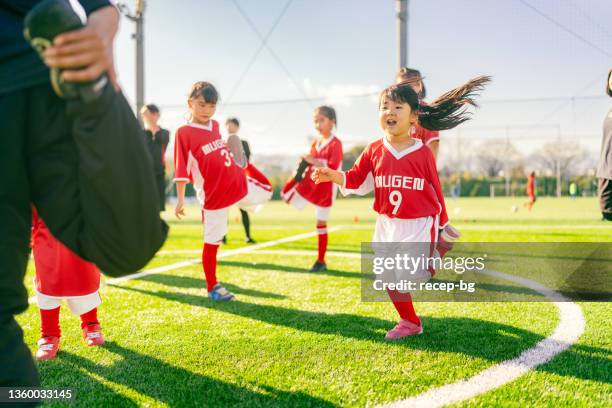 女子キッズサッカーやサッ��カーチームのメンバーがトレーニングを開始する前にウォーミングアップ - サッカー 日本人 ストックフォトと画像