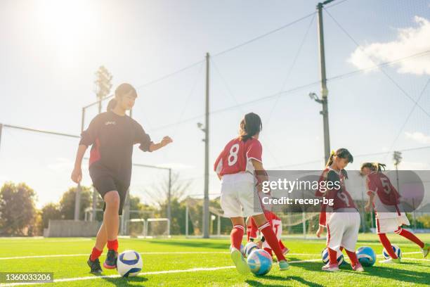 members of female kids' soccer and football team training and dribbling to improve their skills - sporten stockfoto's en -beelden