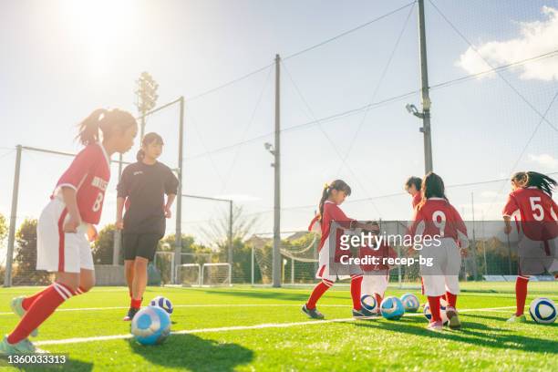 members of female kids' soccer and football team training and dribbling to improve their skills - japan 12 years girl stock pictures, royalty-free photos & images