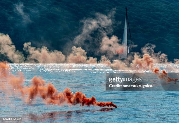 orange colored smoke grenade with sail boats. distress call - distress flare stock pictures, royalty-free photos & images