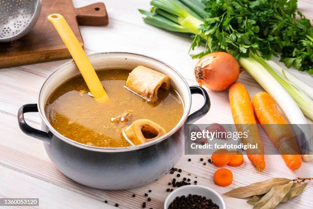 healthy homemade bone broth in a cooking pan - broth stock pictures, royalty-free photos & images