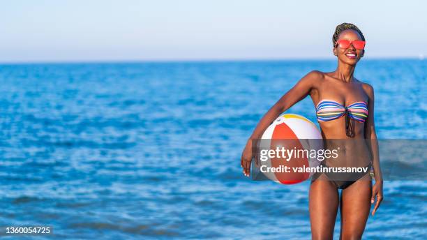african woman having fun with beach ball at the beach - bola de praia imagens e fotografias de stock