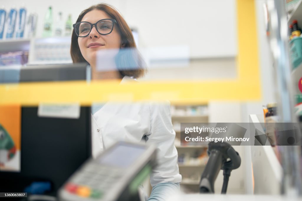 Friendly pharmacist behind counter in drugstore