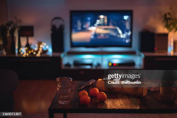 dark indoor scene with candles, clementines and fairy lights  in front of a tv, germany - bildschirme stock-fotos und bilder