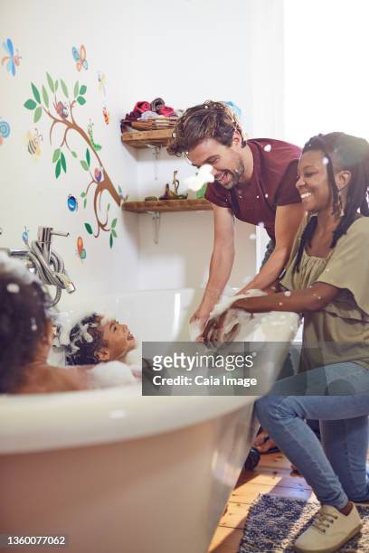 playful parents giving daughters bubble bath - kid bath mother stock-fotos und bilder