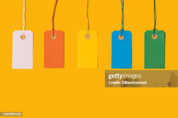 five white, orange, yellow, blue and green cardboard price tags with string on yellow background. pricing, ideas, groups, ordering, design and sales concept. - étiqueter photos et images de collection
