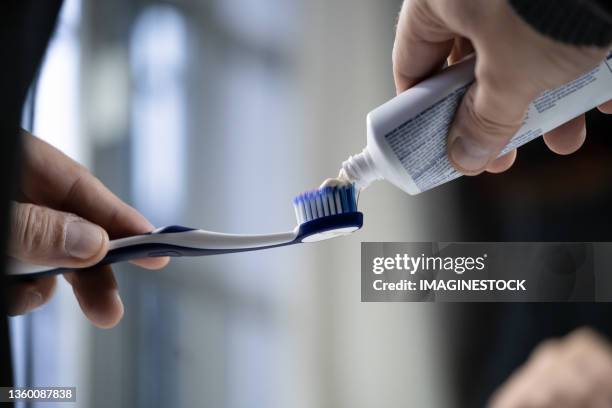 close-up of hand using toothpaste on her toothbrush - nur erwachsene stock-fotos und bilder