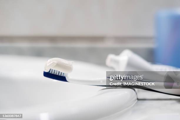 toothbrush on bathroom sink - 歯みがき粉 ストックフォトと画像