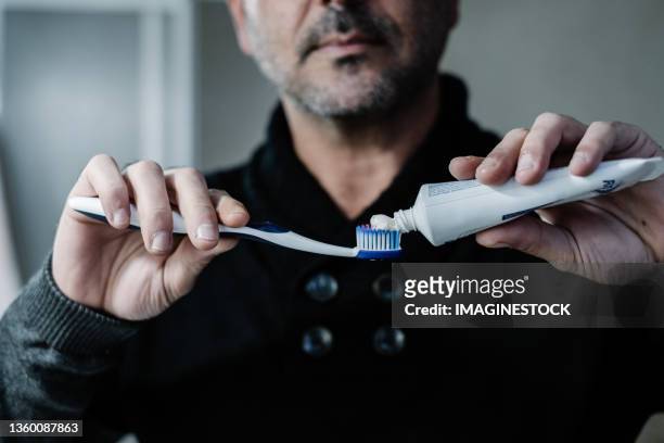 man applying toothpaste to brush - brush teeth stock pictures, royalty-free photos & images