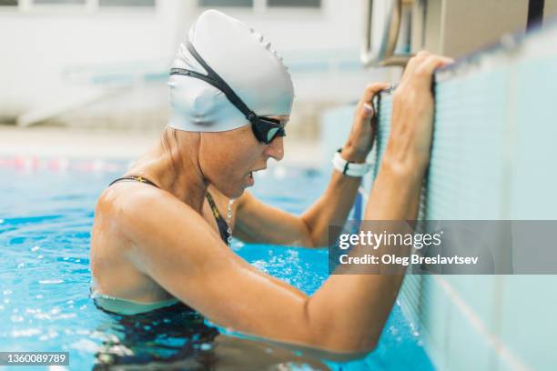 tired female athlete catching her breathe after powerful swimming training. true emotions - finale wedstrijd stockfoto's en -beelden