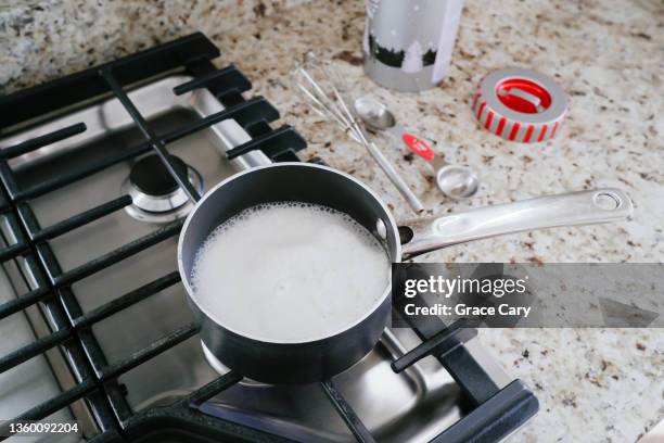 milk boils in pot on gas cooktop - hervir fotografías e imágenes de stock