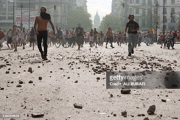 Demonstrators run on a stone-strewn street near Congress during protests against the government of Argentine President Fernando de la Rua 20 December...