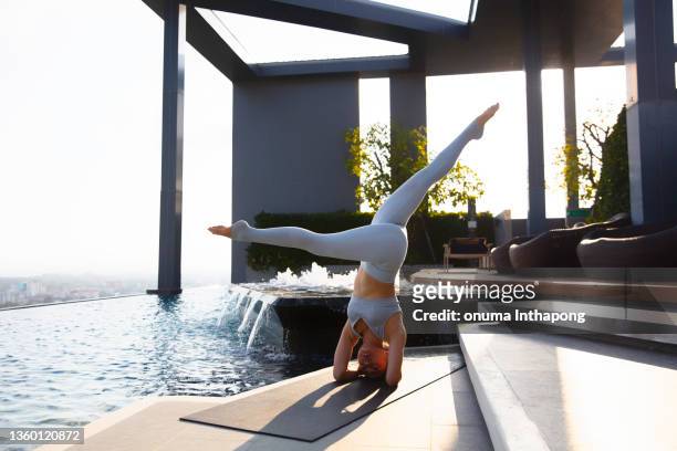 professional yoga practice yoga beside pool at executive top roof of condominium, urban health lifestyle - rooftop pool imagens e fotografias de stock
