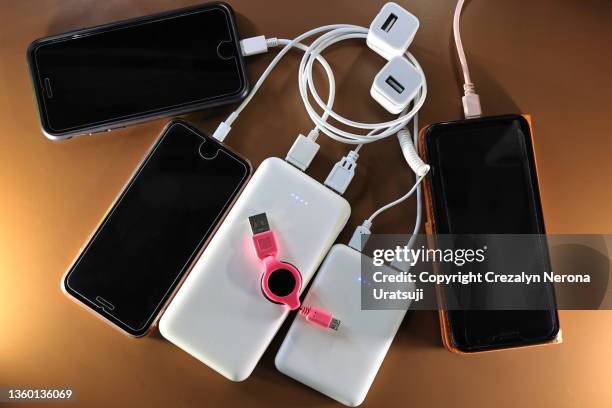 smartphones being charge with portable power banks - powerbank stock-fotos und bilder