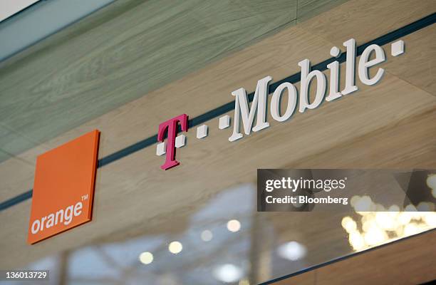 The France Telecome SA's Orange brand logo, left and the Deutsche Telekom AG's T-Mobile brand logo are displayed outside a store operated by...
