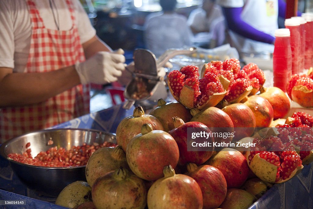 Man squeezing fresh pomegranates at street market